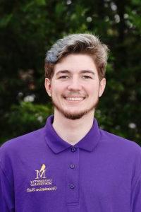 Photo of Cole Broadhead wearing a purple Orientation Leader polo shirt. 