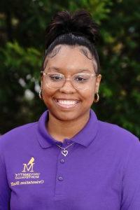 Photo of Skyelar Thomas wearing a purple Orientation Leader polo shirt.